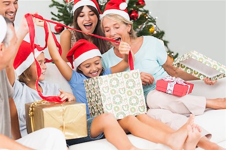 simsearch:400-06874610,k - Happy family at christmas opening gifts together on the couch Foto de stock - Super Valor sin royalties y Suscripción, Código: 400-06873479