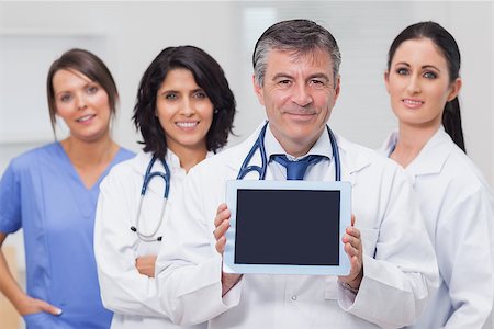 Doctor showing tablet pc with his team behind him Stock Photo - Budget Royalty-Free & Subscription, Code: 400-06873873