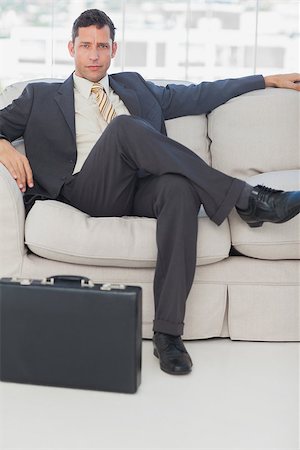 simsearch:400-06879262,k - Serious businessman sitting with legs crossed on the couch with his briefcase Stock Photo - Budget Royalty-Free & Subscription, Code: 400-06884105