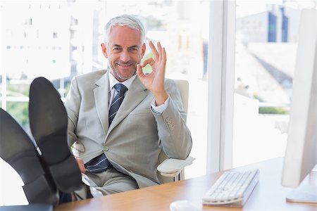 Happy businessman giving ok sign with feet up on his desk Stock Photo - Budget Royalty-Free & Subscription, Code: 400-06884340