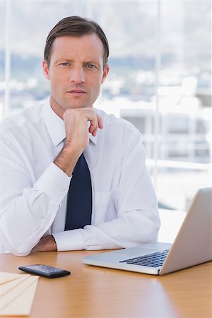 simsearch:400-06884500,k - Handsome businessman posing in his office sitting next to his desk Stock Photo - Budget Royalty-Free & Subscription, Code: 400-06884497