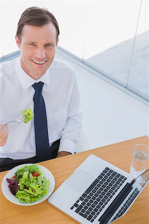 simsearch:400-06884500,k - Overhead of a smiling businessman eating a salad during the lunch time Stock Photo - Budget Royalty-Free & Subscription, Code: 400-06884524