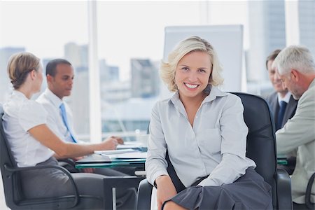 simsearch:400-06879262,k - Attractive businesswoman posing in the boardroom with colleagues discussing behind Stock Photo - Budget Royalty-Free & Subscription, Code: 400-06884564
