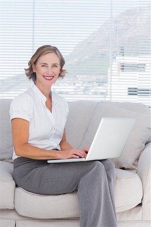 Attractive businesswoman using laptop and sitting on sofa Stock Photo - Budget Royalty-Free & Subscription, Code: 400-06884695