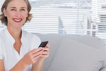 Smiling businesswoman using her mobile phone in bright office Stock Photo - Budget Royalty-Free & Subscription, Code: 400-06884710