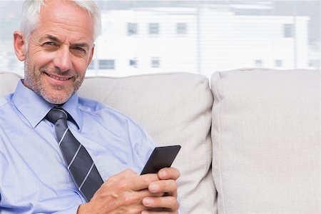 Happy businessman using smartphone on couch in staffroom Stock Photo - Budget Royalty-Free & Subscription, Code: 400-06884771