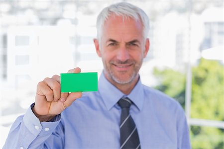 simsearch:400-06879262,k - Happy businessman showing green business card in his office Stock Photo - Budget Royalty-Free & Subscription, Code: 400-06884825