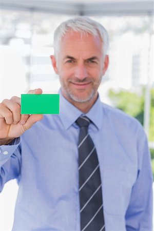 simsearch:400-06879262,k - Smiling businessman showing green business card in his office Stock Photo - Budget Royalty-Free & Subscription, Code: 400-06884826