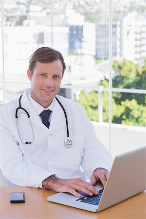 simsearch:695-05771285,k - Smiling doctor working on his laptop in his office Foto de stock - Royalty-Free Super Valor e Assinatura, Número: 400-06884897