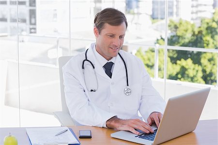 simsearch:695-05771285,k - Happy doctor working on a laptop on his desk Foto de stock - Royalty-Free Super Valor e Assinatura, Número: 400-06884900