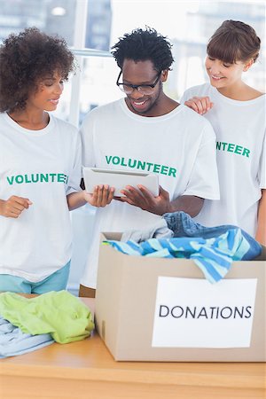 donation - Cheerful volunteers looking at a tablet pc in front of a donations box Stock Photo - Budget Royalty-Free & Subscription, Code: 400-06885699