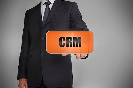 simsearch:400-06886051,k - Businessman touching orange tag with the word crm written on it on grey background Stock Photo - Budget Royalty-Free & Subscription, Code: 400-06885951