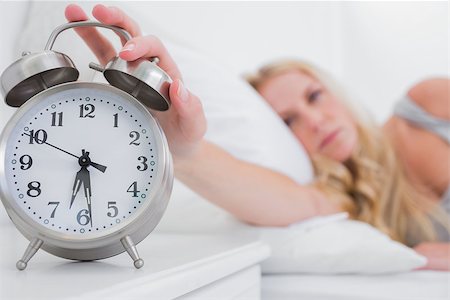 Tired woman turning off the alarm clock in her bed Photographie de stock - Aubaine LD & Abonnement, Code: 400-06886508