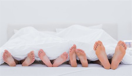 Family showing their feet while lying on bed Photographie de stock - Aubaine LD & Abonnement, Code: 400-06886590