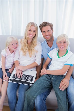 Smiling family using laptop in their living room and looking at camera Stock Photo - Budget Royalty-Free & Subscription, Code: 400-06886615