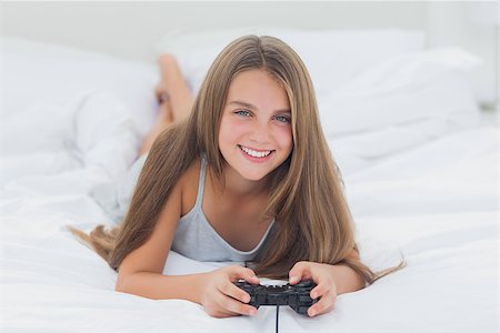 pajamas video game pictures - Young girl playing video games while she is lying on her bed Stock Photo - Budget Royalty-Free & Subscription, Code: 400-06887629
