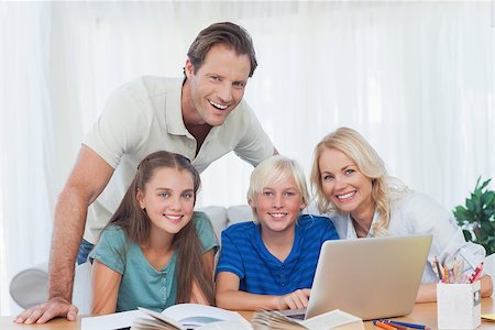 Smiling family using the laptop together to do homework in living room Stock Photo - Budget Royalty-Free & Subscription, Code: 400-06887716