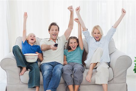 family home tv caucasian - Family watching television and raising arms while holding pop corn Stock Photo - Budget Royalty-Free & Subscription, Code: 400-06887751