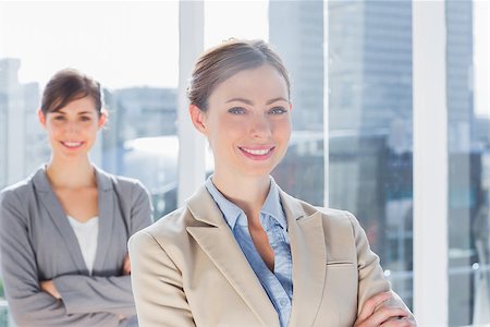 simsearch:400-07275828,k - Happy businesswomen standing with arms crossed in bright office Photographie de stock - Aubaine LD & Abonnement, Code: 400-06887846