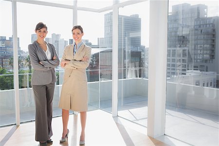 simsearch:400-07275828,k - Smiling businesswomen standing in bright office with arms crossed Photographie de stock - Aubaine LD & Abonnement, Code: 400-06887841