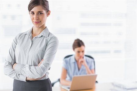 simsearch:400-07275828,k - Businesswoman smiling at camera with arms crossed and colleague behind Photographie de stock - Aubaine LD & Abonnement, Code: 400-06887989