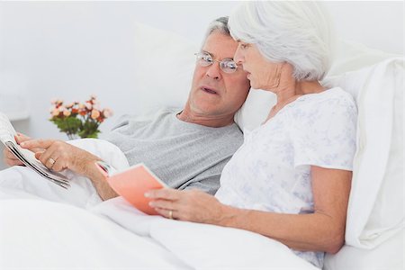 simsearch:400-06888132,k - Mature couple looking at a newspaper in bed Photographie de stock - Aubaine LD & Abonnement, Code: 400-06888146
