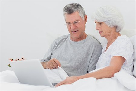 Man with wife pointing at a laptop in bed Stock Photo - Budget Royalty-Free & Subscription, Code: 400-06888155
