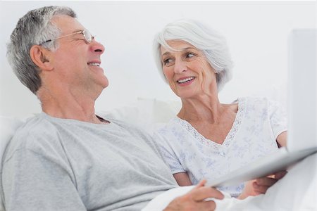 Cheerful mature couple using a laptop together in bed Stock Photo - Budget Royalty-Free & Subscription, Code: 400-06888157