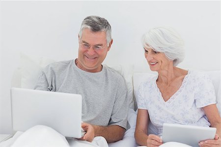 Mature man showing something on his laptop to his wife on bed Stock Photo - Budget Royalty-Free & Subscription, Code: 400-06888151