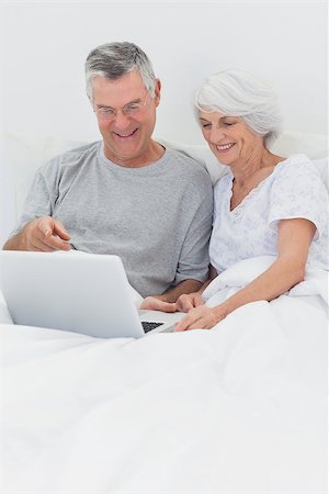 simsearch:400-06888132,k - Mature couple using a laptop together in bed Photographie de stock - Aubaine LD & Abonnement, Code: 400-06888152