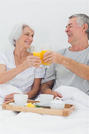 simsearch:628-02615261,k - Cheerful couple clinking their orange juice glasses while having breakfast in bed Stockbilder - Microstock & Abonnement, Bildnummer: 400-06888170
