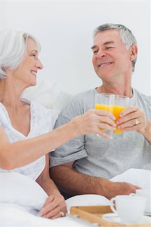 simsearch:628-02615261,k - Couple clinking their orange juice glasses while having breakfast in bed Stockbilder - Microstock & Abonnement, Bildnummer: 400-06888172