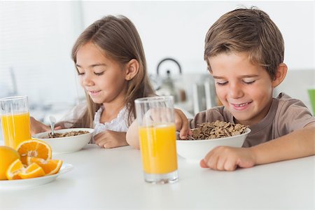 simsearch:400-06871178,k - Cheerful siblings eating cereal together while they are having breakfast Stock Photo - Budget Royalty-Free & Subscription, Code: 400-06888484