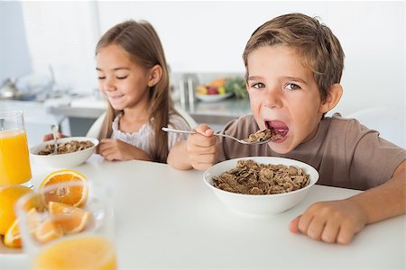 simsearch:400-06871178,k - Boy eating cereal next to his sister during the breakfast Stock Photo - Budget Royalty-Free & Subscription, Code: 400-06888486