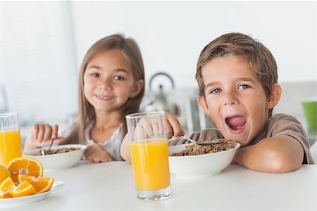 simsearch:400-06871178,k - Siblings eating cereal together while they are having breakfast Stock Photo - Budget Royalty-Free & Subscription, Code: 400-06888483