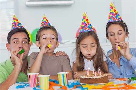 Family with party horn celebrating their daughter party who is blowing her candles Stock Photo - Budget Royalty-Free & Subscription, Code: 400-06888509