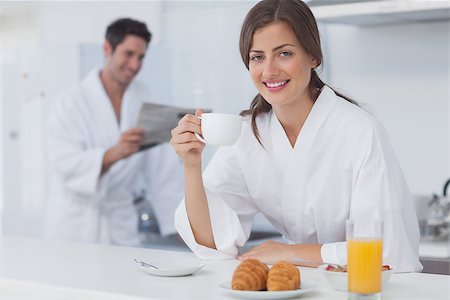 simsearch:400-06871178,k - Woman with a dressing gown having breakfast while her husband is reading a newspaper on the background Stock Photo - Budget Royalty-Free & Subscription, Code: 400-06888654