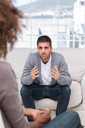 psicólogo - Upset man speaking to a therapist while she is listening to him attentively Foto de stock - Royalty-Free Super Valor e Assinatura, Número: 400-06880032