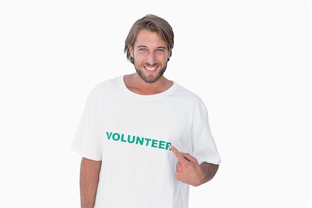 Smiling man pointing to his volunteer tshirt on white background Stockbilder - Microstock & Abonnement, Bildnummer: 400-06880331