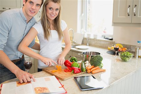 Woman cutting vegetables with man reading the cookery book in kitchen Stock Photo - Budget Royalty-Free & Subscription, Code: 400-06881685