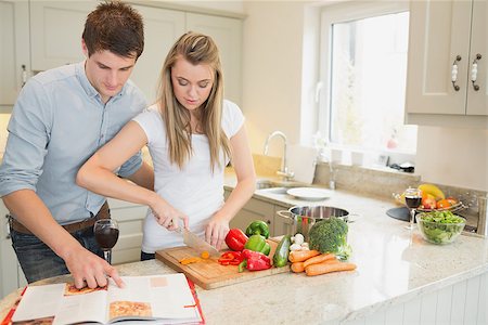 Woman cutting vegetables with man reading the cookbook in kitchen Stock Photo - Budget Royalty-Free & Subscription, Code: 400-06881682