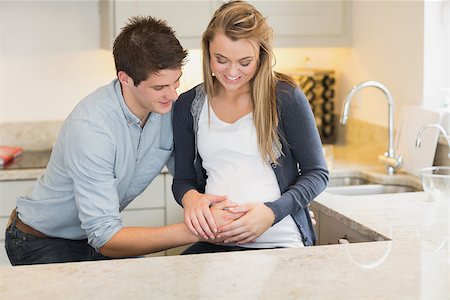 simsearch:400-07955632,k - Man touching partners pregnant belly in kitchen Photographie de stock - Aubaine LD & Abonnement, Code: 400-06881740