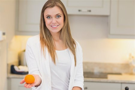 simsearch:400-06871178,k - Woman with orange in her hand in kitchen Stock Photo - Budget Royalty-Free & Subscription, Code: 400-06881775