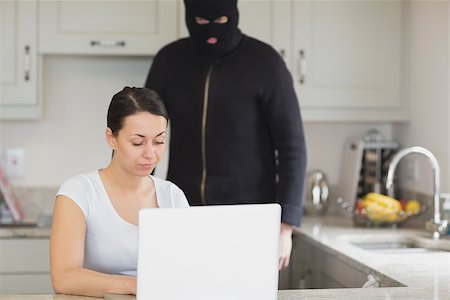 Woman typing on the laptop while burglar looking at it in kitchen Foto de stock - Super Valor sin royalties y Suscripción, Código: 400-06881865