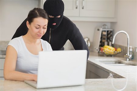 Woman using laptop while burgler is watching in kitchen Stock Photo - Budget Royalty-Free & Subscription, Code: 400-06881867