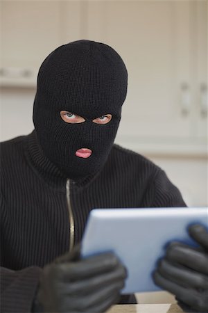 simsearch:400-06803569,k - Suspicious burgler holding tablet pc in kitchen Stock Photo - Budget Royalty-Free & Subscription, Code: 400-06881870