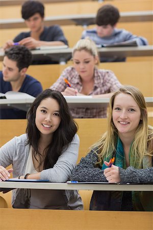 simsearch:400-04035793,k - Smiling students sitting in a lecture hall while taking notes Foto de stock - Super Valor sin royalties y Suscripción, Código: 400-06881954