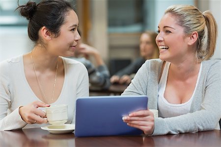 Two students chatting and using the tablet pc while being in a coffee shop Stock Photo - Budget Royalty-Free & Subscription, Code: 400-06881995