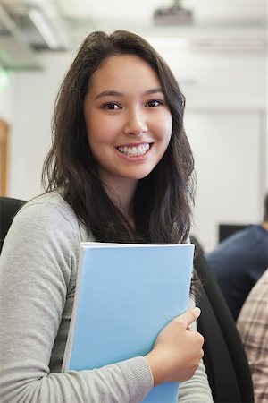 simsearch:400-07267978,k - Student standing in the computer room and holding a folder while smiling Stock Photo - Budget Royalty-Free & Subscription, Code: 400-06881997