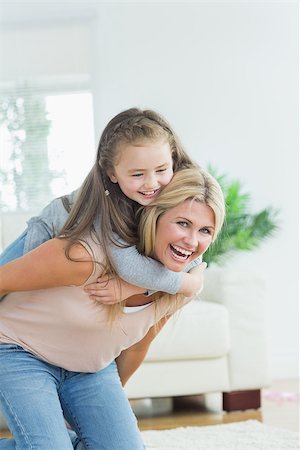 Laughing mother giving daughter a piggy bank in the living room Stock Photo - Budget Royalty-Free & Subscription, Code: 400-06882148